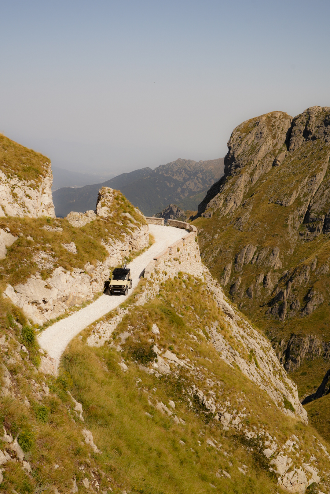 Suzuki Jimny driving the Salt Road Italy 4x4 with mountain views and bikers on the trail